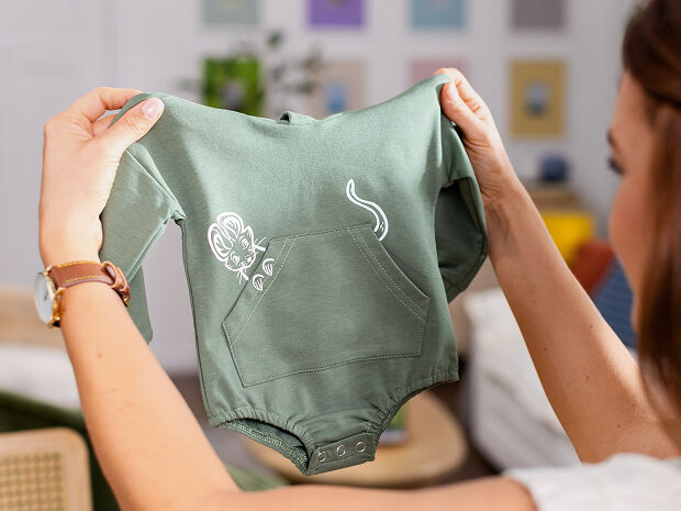Person holding a finished iron on project on a green shirt